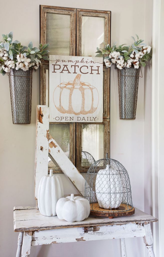 Pumpkin patch sign above a small side table with ceramic white pumpkins.