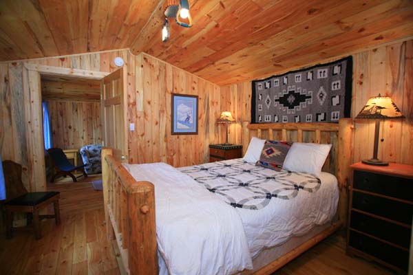 A room from Rimrack Ranch with all wood interior and cabinlog bedpost with quilted bedspread