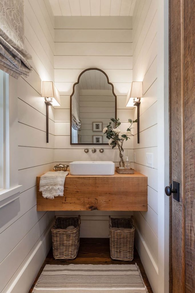 A sink with wood countertop and white shiplap on walls.