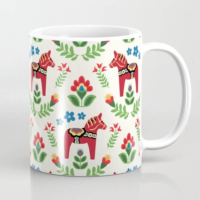 A birthday gift mug with images of red Dala horses and cartoonish foliage