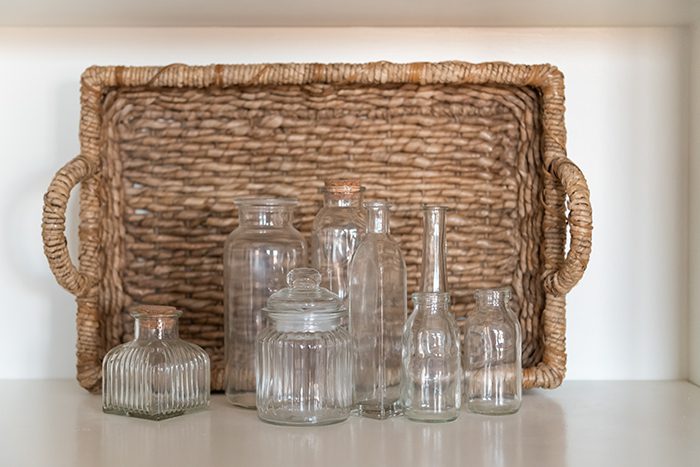 A collection of small clear glass bottles in front of a basket.