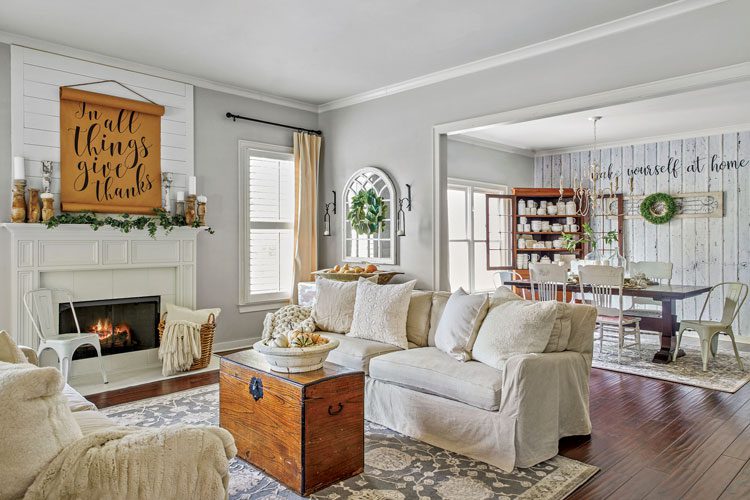 fall farmhouse living room with sign above mantle white couches and dining room