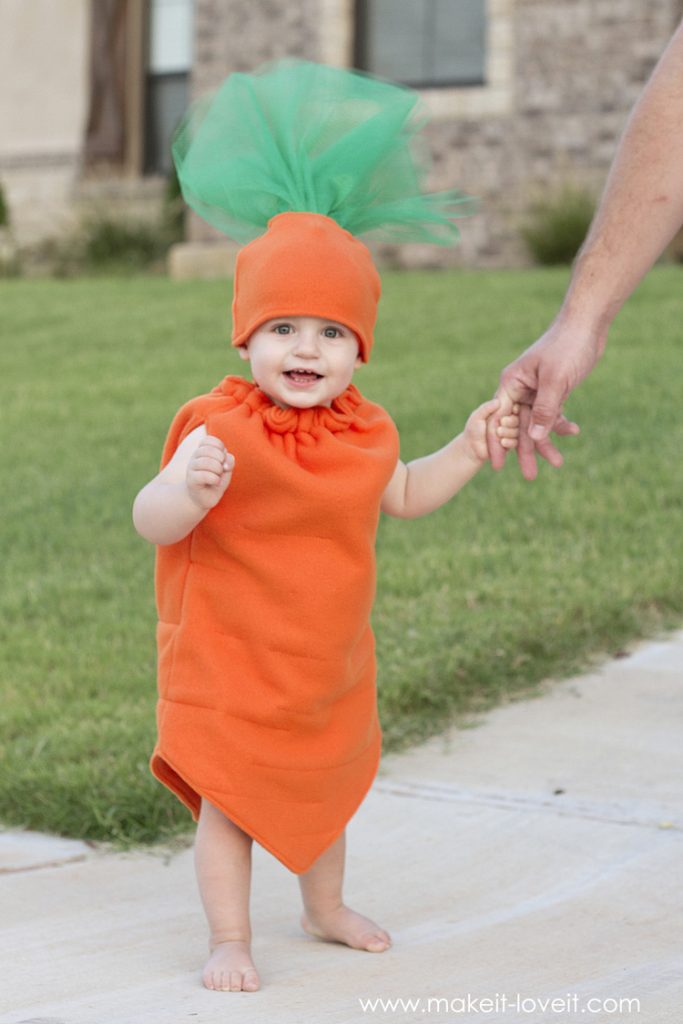 Toddler dressed as an orange felt carrot with tufts of green tulle coming out of his hat as the stem.