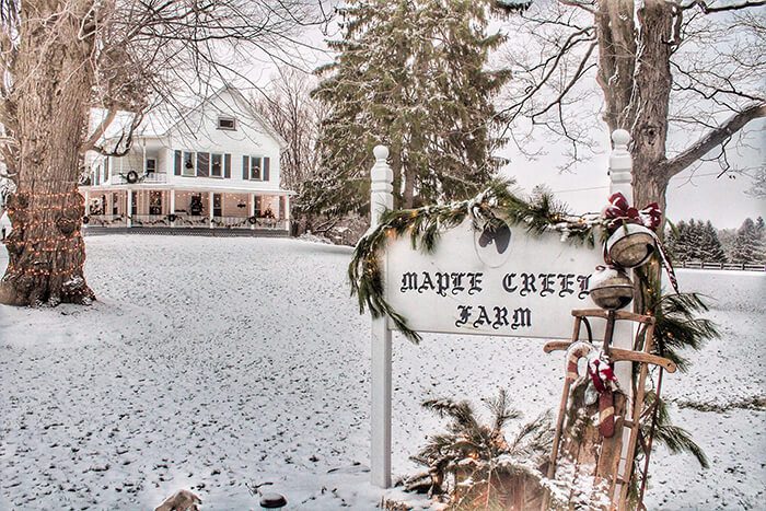 Exterior of the farm in the snow, with Maple Creek Market Farm sign