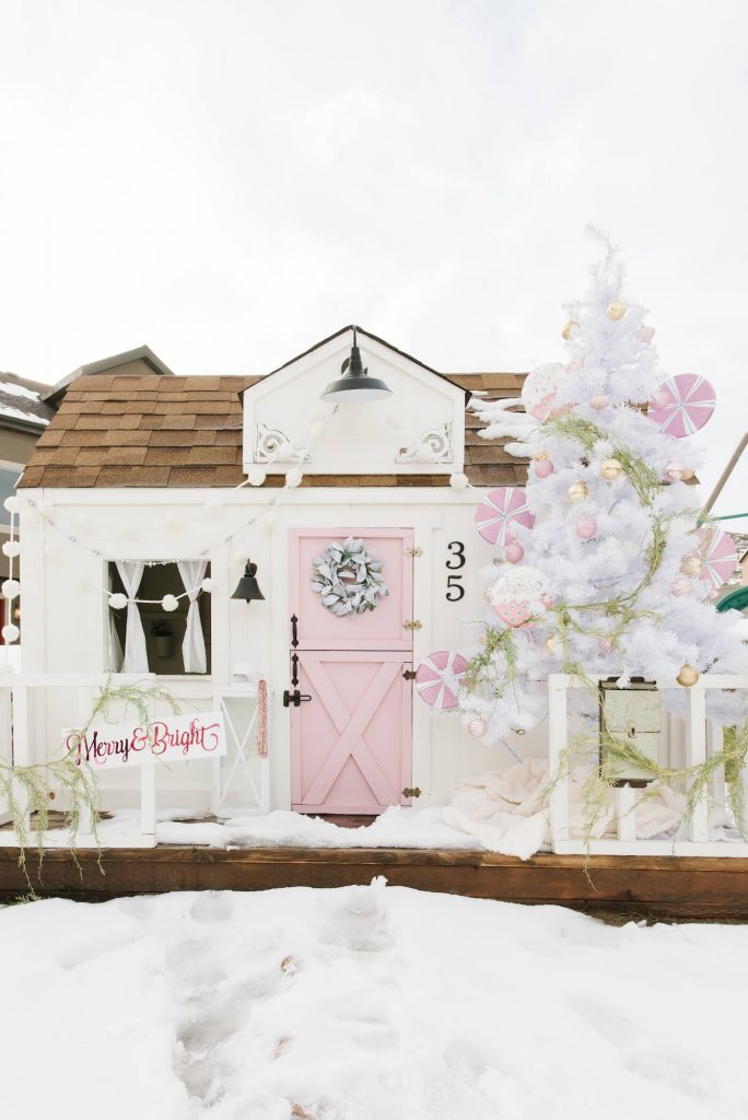 Exterior of playhouse with pink door and white Christmas tree