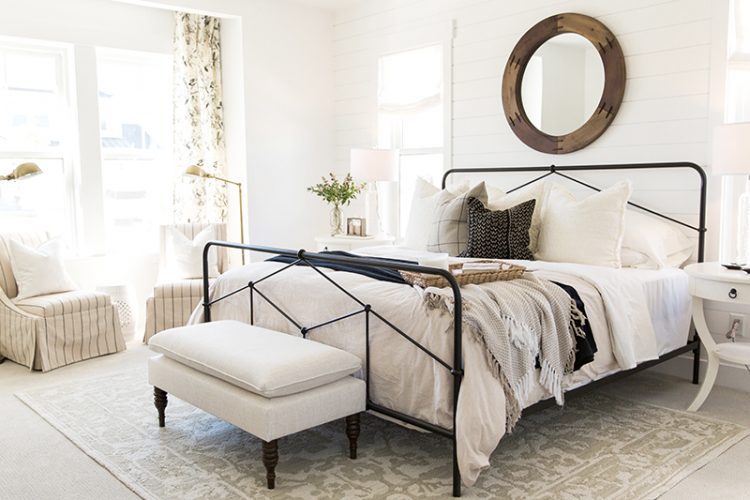 modern farmhouse style bedroom with iron bedframe window perisan rug and footstool