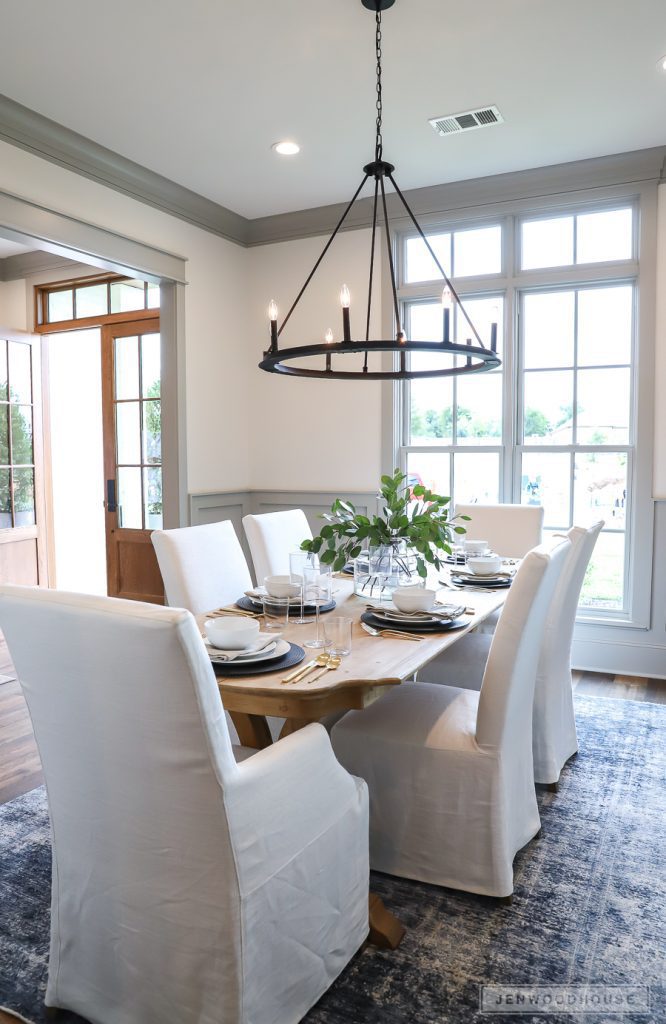 dining room with modern chandelier bright windows covered chairs and rustic table in modern farmhouse style