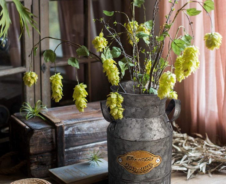 Rustic fall decor: metal milk can with leafy branches in it.