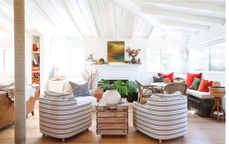 living room with striped chairs white fireplace and exposed post and beam ceiling in decluttering ranch renovation