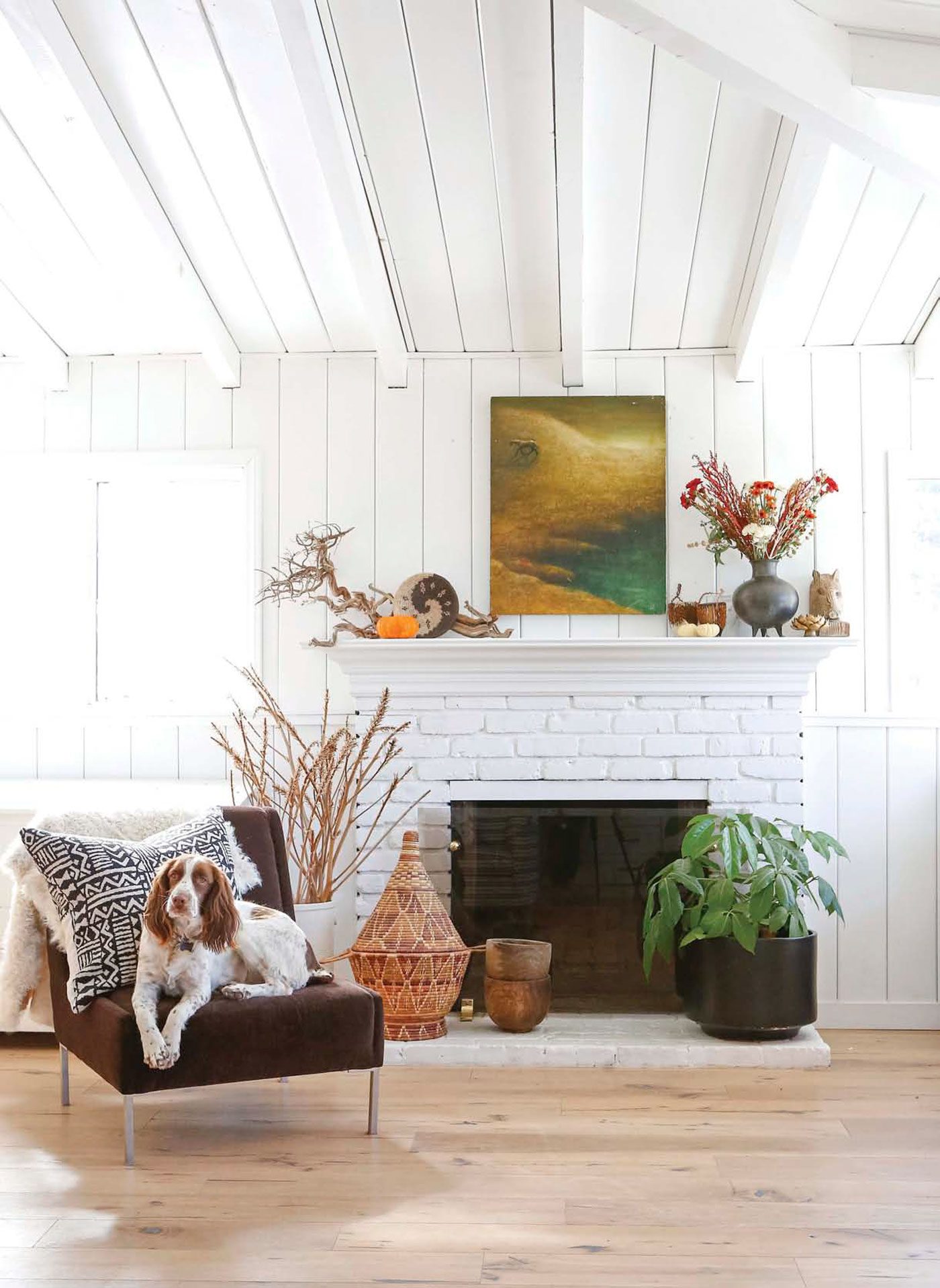 white brick fireplace next to gray chair with dog