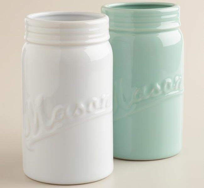 A white ceramic mason jar vase next to a teal ceramic mason jar vase