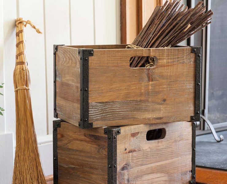 Two stacked wooden crates with a broom resting against their left sides