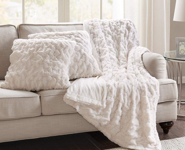 Two white faux fur pillows and matching blanket.