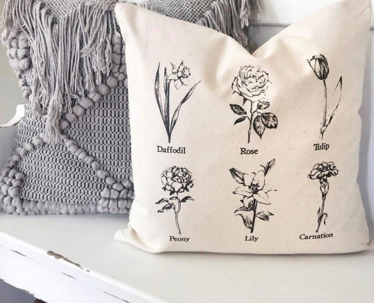 Cream colored pillow with six black, vintage, labeled flower drawings