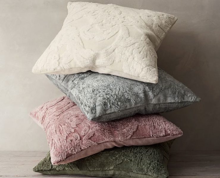 Solid-colored throw pillows with textured antique design patterns.