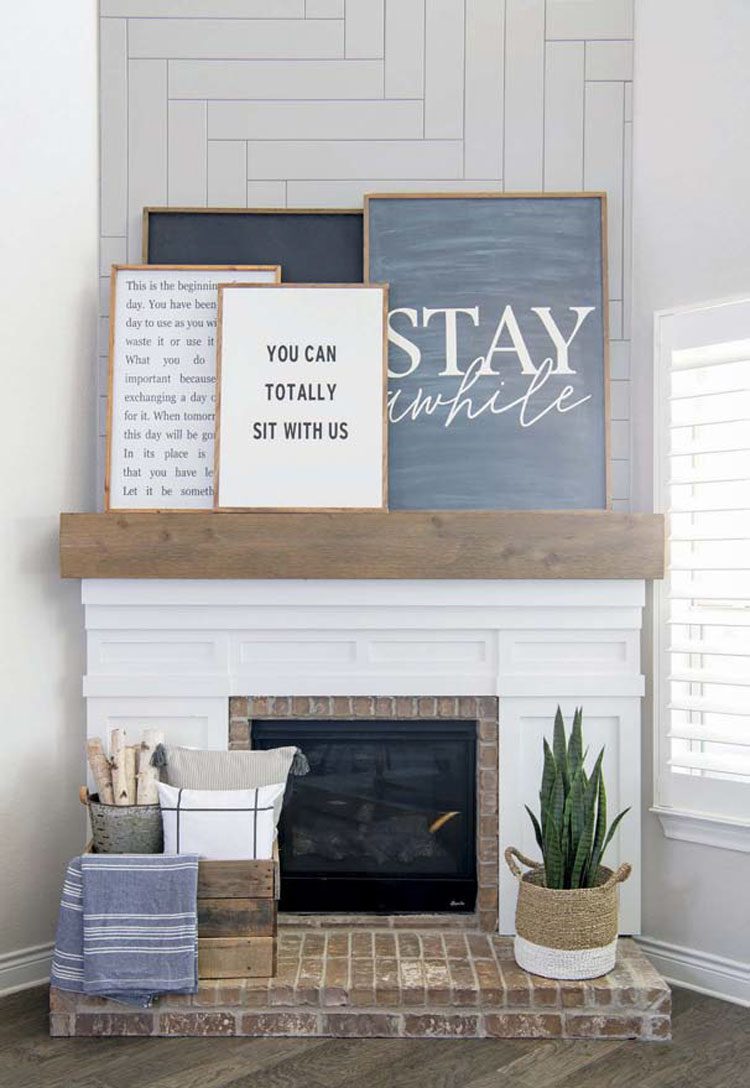 The mantel above their white fireplace has four different pieces of gray-scale sign art layered over each other.