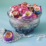 A beautiful clear glass bowl is full of colorful collectible glass ornaments.