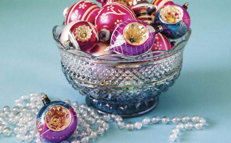 A beautiful clear glass bowl is full of colorful collectible glass ornaments.
