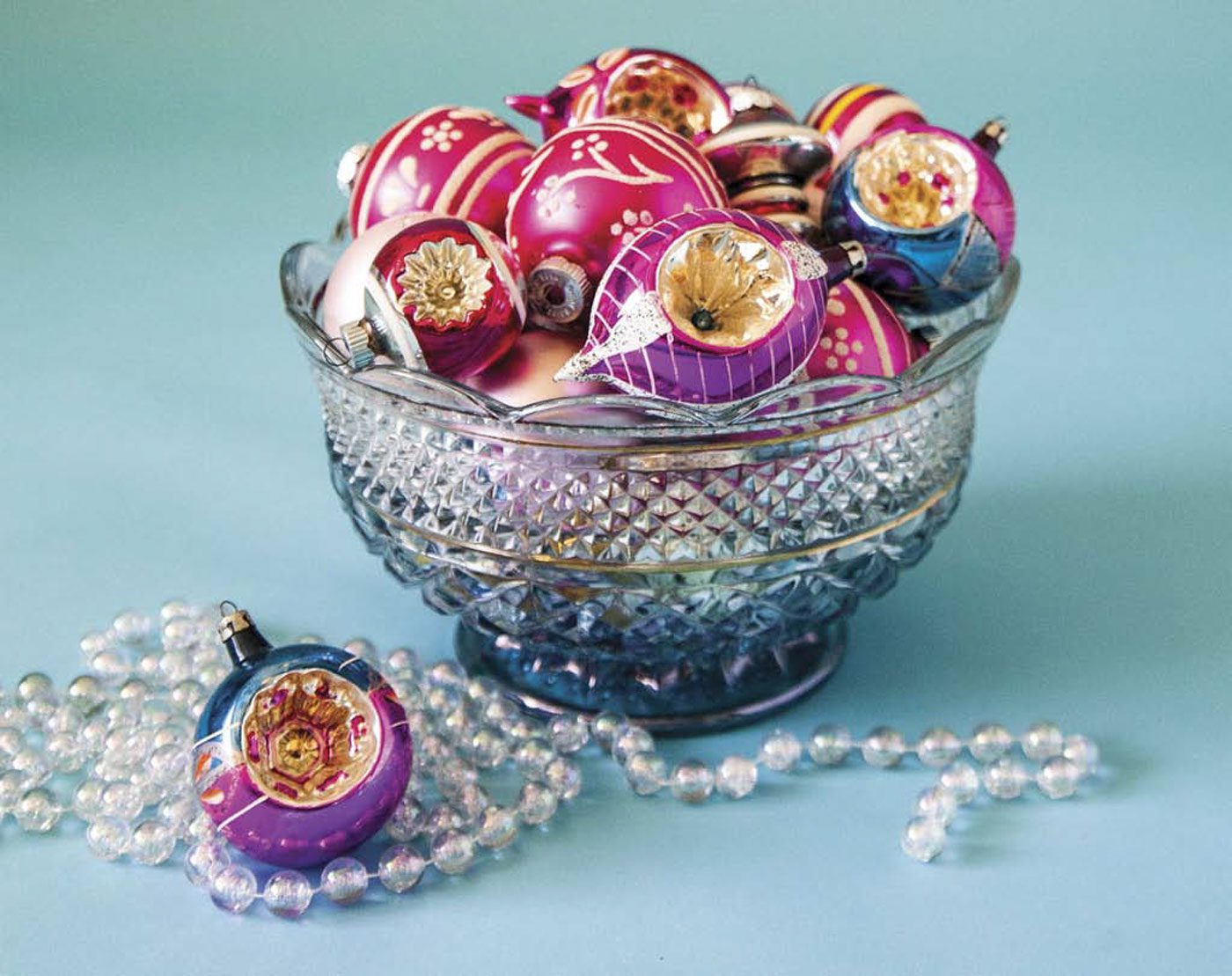 A beautiful clear glass bowl is full of colorful collectible glass ornaments.