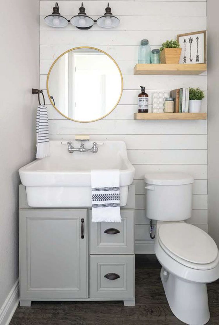 This small Texas farmhouse bathroom has a white shiplap accent wall that pops in the gray scale color palette.
