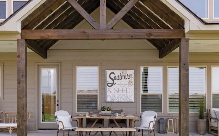 The exterior of this Texas farmhouse has a broad triangular archway over a table ready for guests!