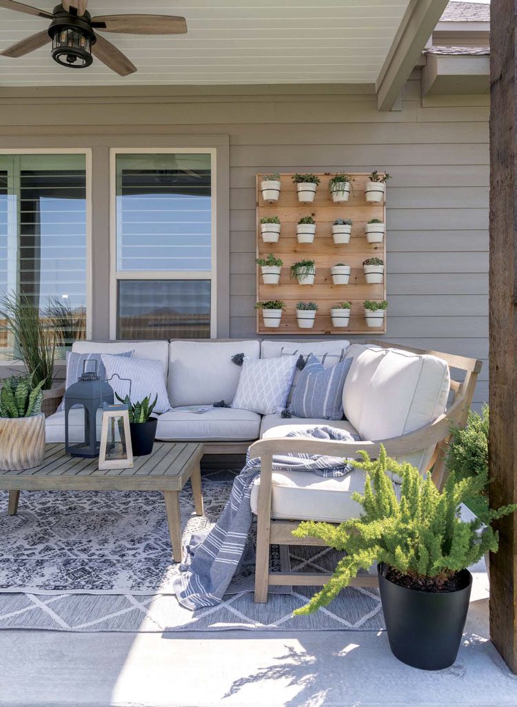 Outside patio space with a DIY potted plant wall rack behind the plush seating area.