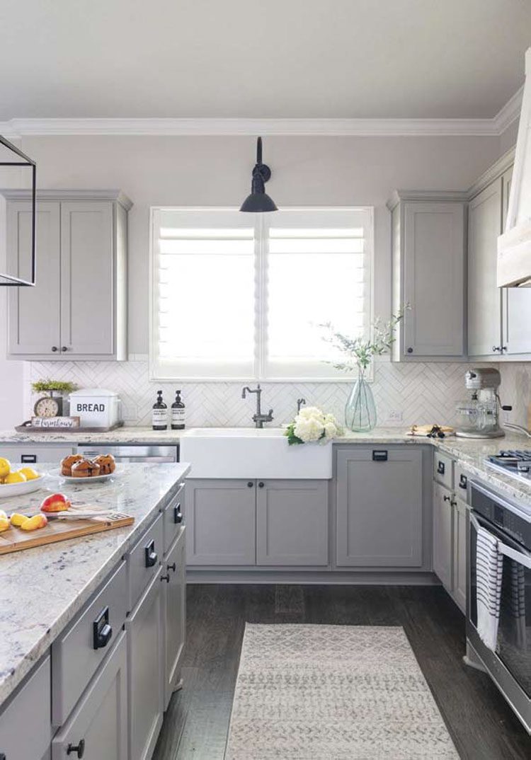 This Texas farmhouse is a gray-scale creation with stone countertops and plenty of naural light coming throught the window above the sink.