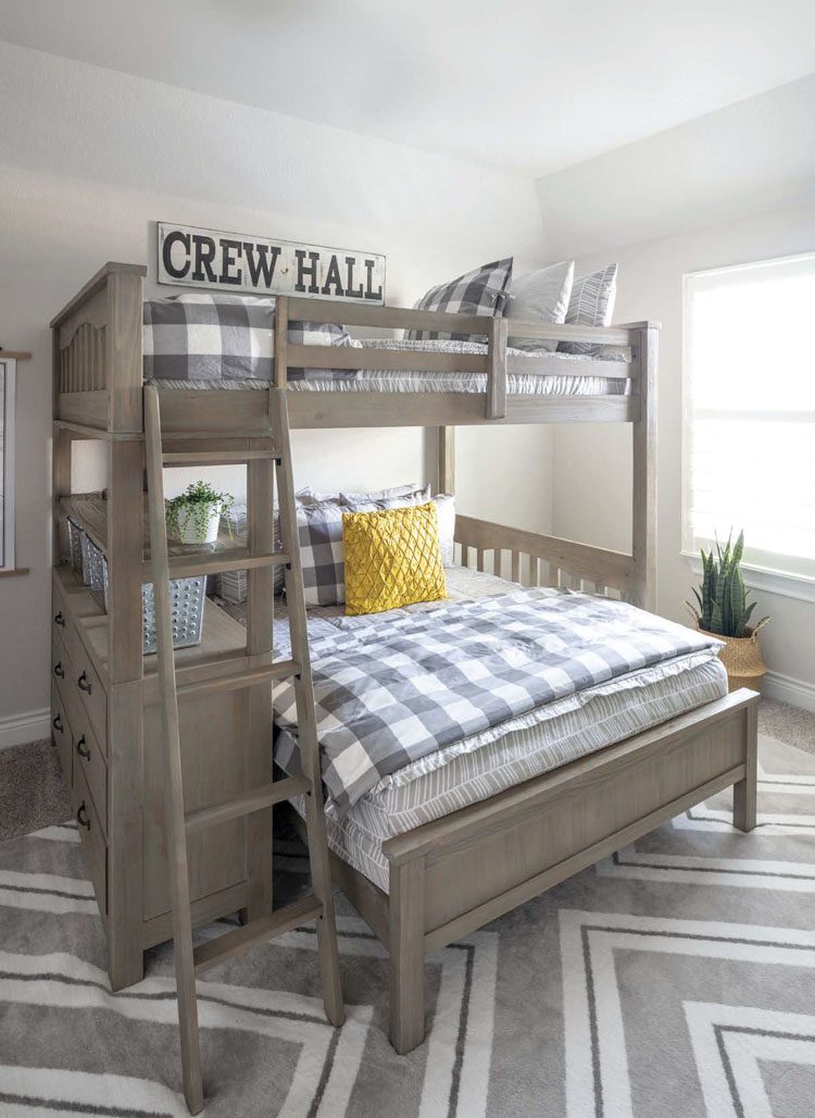 The kids' bedroom has a bunk bed with gray cross-hatched comforters and yellow pillow accents. There's also a black and white, vintage-inspired sign that says "Crew Hall" above the beds.