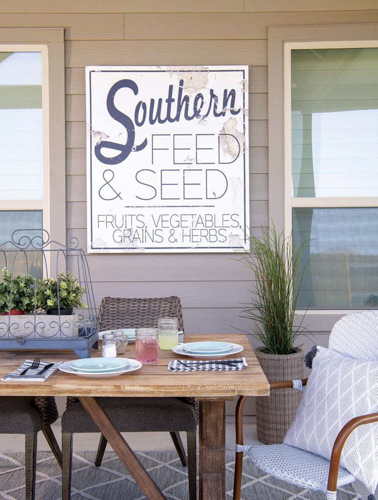 The rustic wall art above their Texas farmhouse outdoor patio table says "Southern Feed & Seed" in a mixture of fonts.