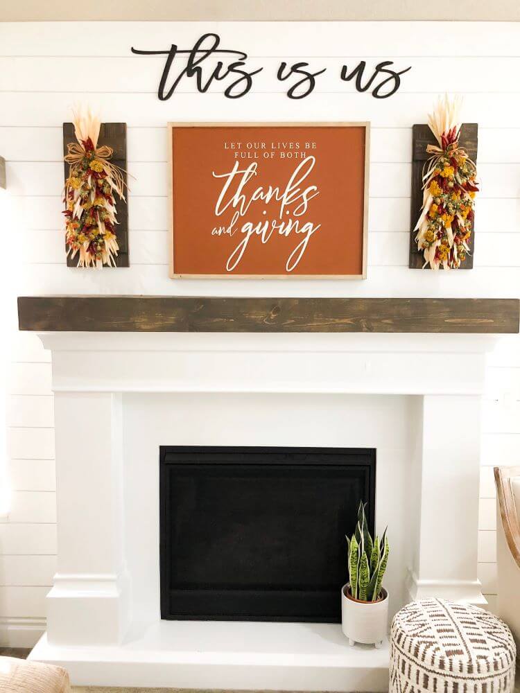 white fireplace with This Is Us sign and fall mantel