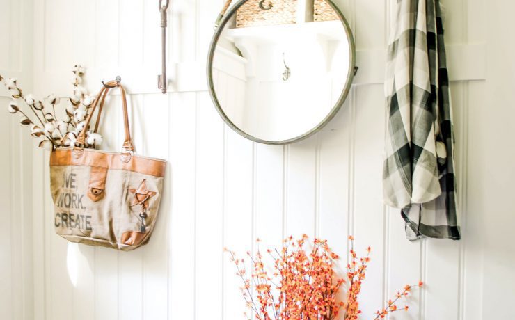 Nina's mudroom uses everyday items to create a chic upcycled fall look. She has a flannel hanging by a hook above rain boots-turned planters and a woven basket.