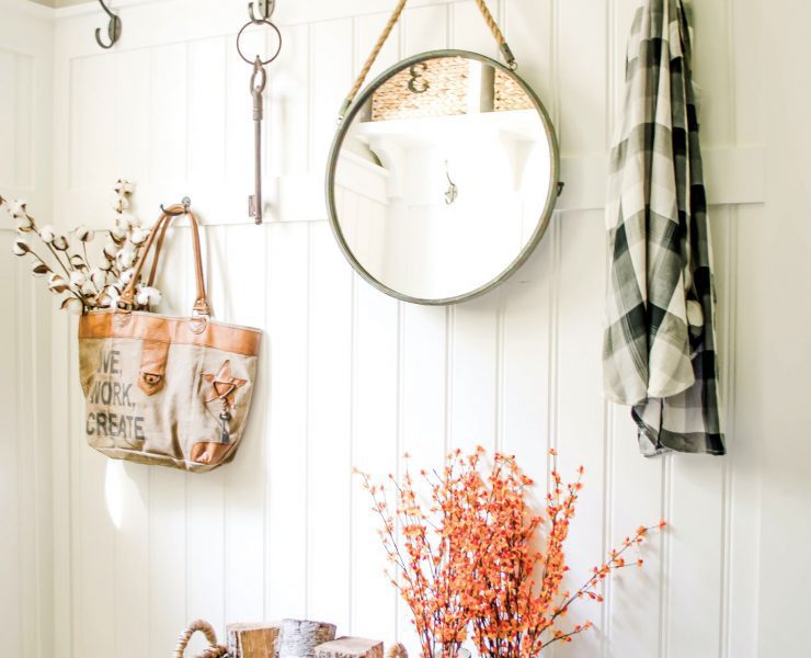 Nina's mudroom uses everyday items to create a chic upcycled fall look. She has a flannel hanging by a hook above rain boots-turned planters and a woven basket.