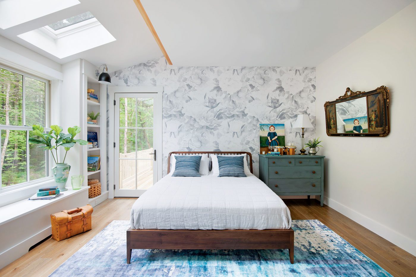 This farm-cottage bedroom shows off the comforts of home with a white comforter, peel-away gray patterned wallpaper and plenty of windows for natural light.
