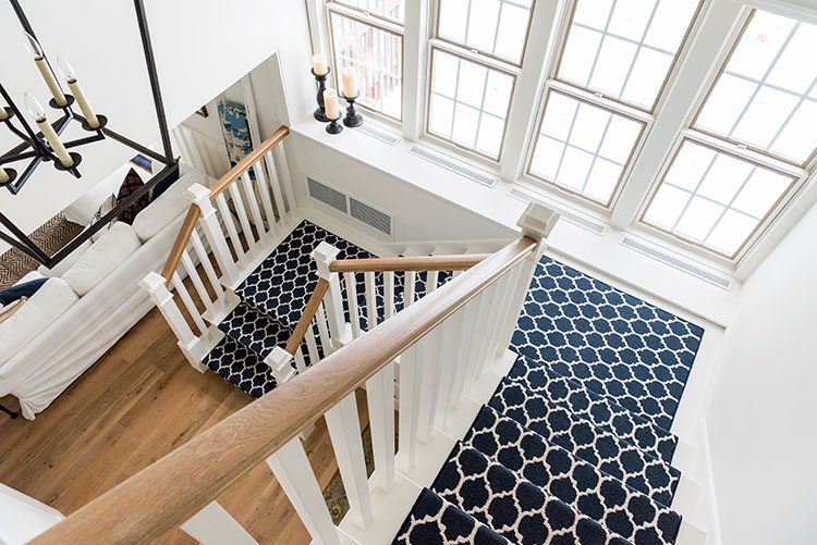 The staircase design has a railing has a plain wood top while the rest of it has been painted white to match the walls and windowsill.