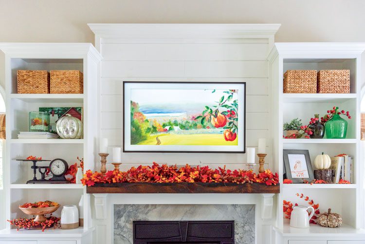 Nina's TV is framed with a black border and is disguised as a piece of art by constantly displaying family artwork. It hangs above their fireplace.