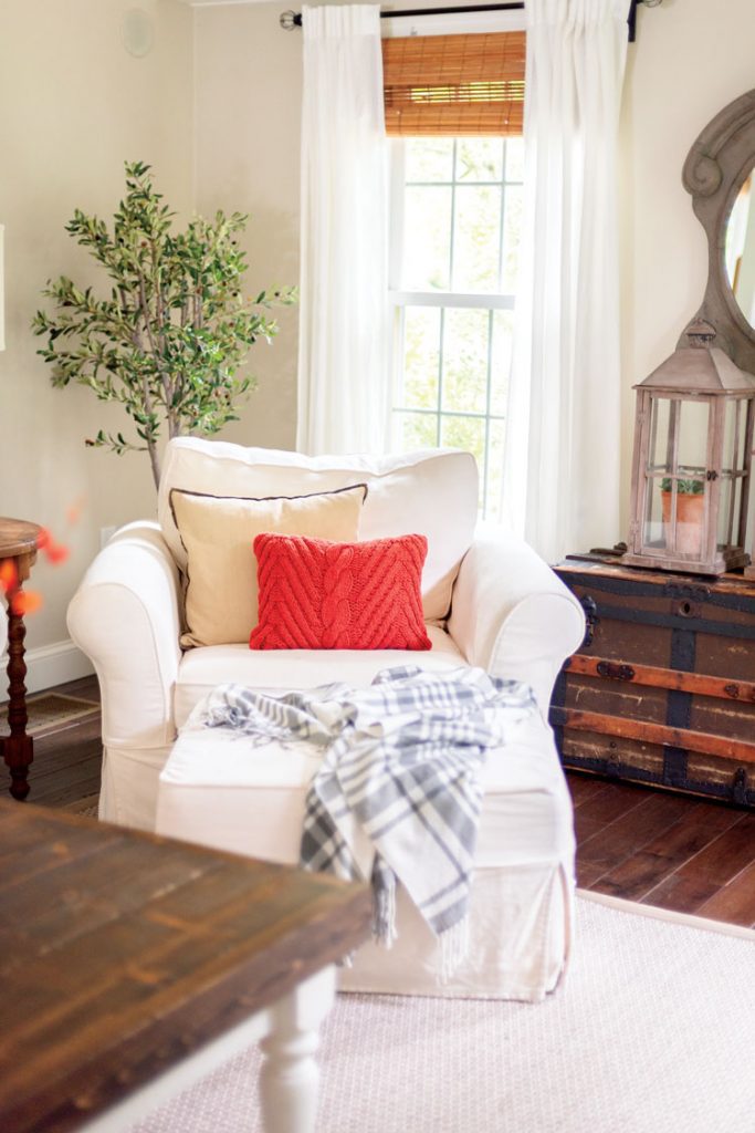 Nina added a bright orange pillow to the plush white armchair in her living room to add a splash of cheer.