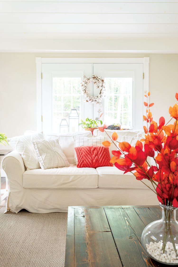 Nina is a master of upcycled fall decor. Her rustic wood coffee table looks beautiful in contrast with her white couch with an orange pillow accent.