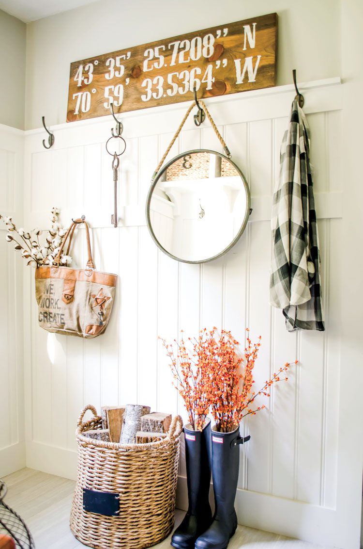 Nina's mudroom uses everyday items to create a chic upcycled fall look. She has a flannel hanging by a hook above rain boots-turned planters and a woven basket.