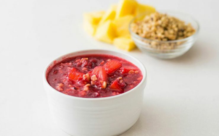 The sweetest and tangiest of Thanksgiving recipes, this one is a white bowl filled with cranberry sauce that has pineapple pieces in it.