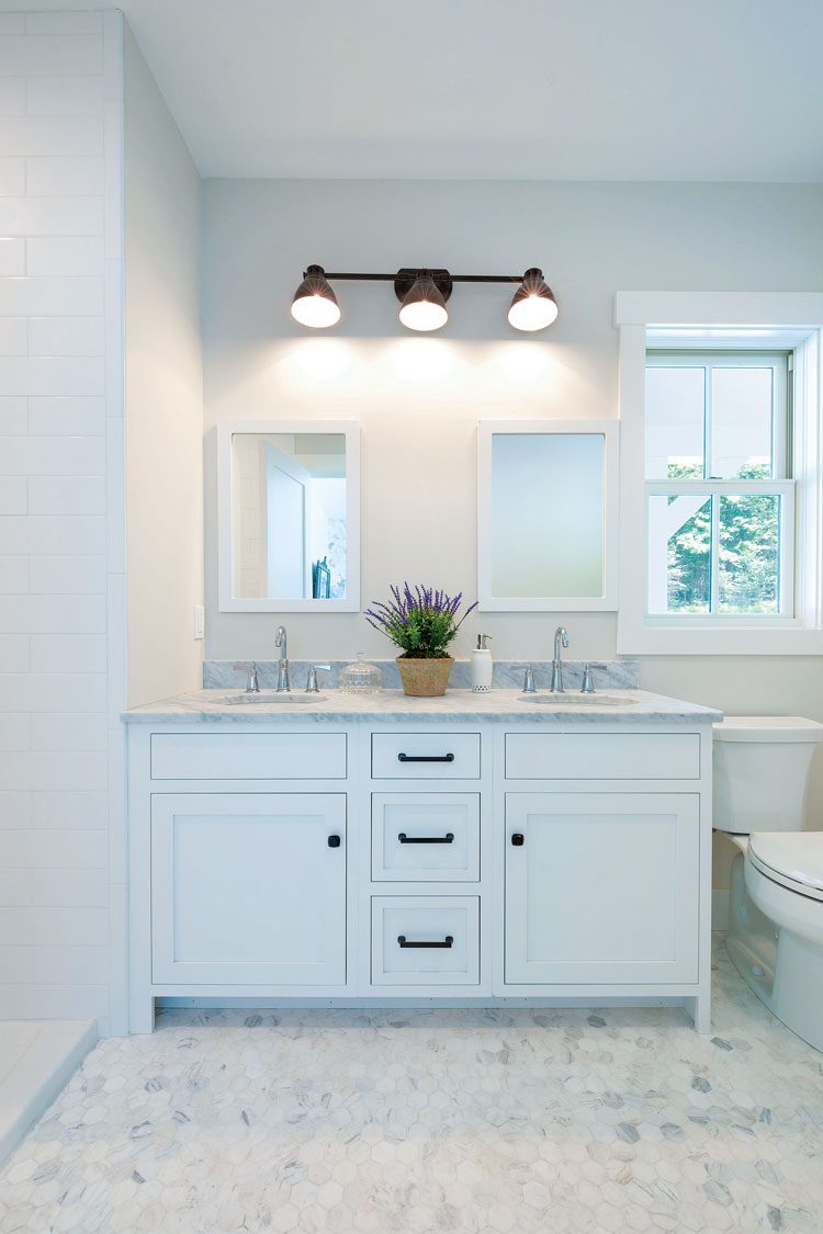The bathroom has off-white, hex tile flooring paired with white cabinetry.