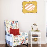 A colorful gingham and floral patterned arm-chair with a white side table in front of a white paint wall.