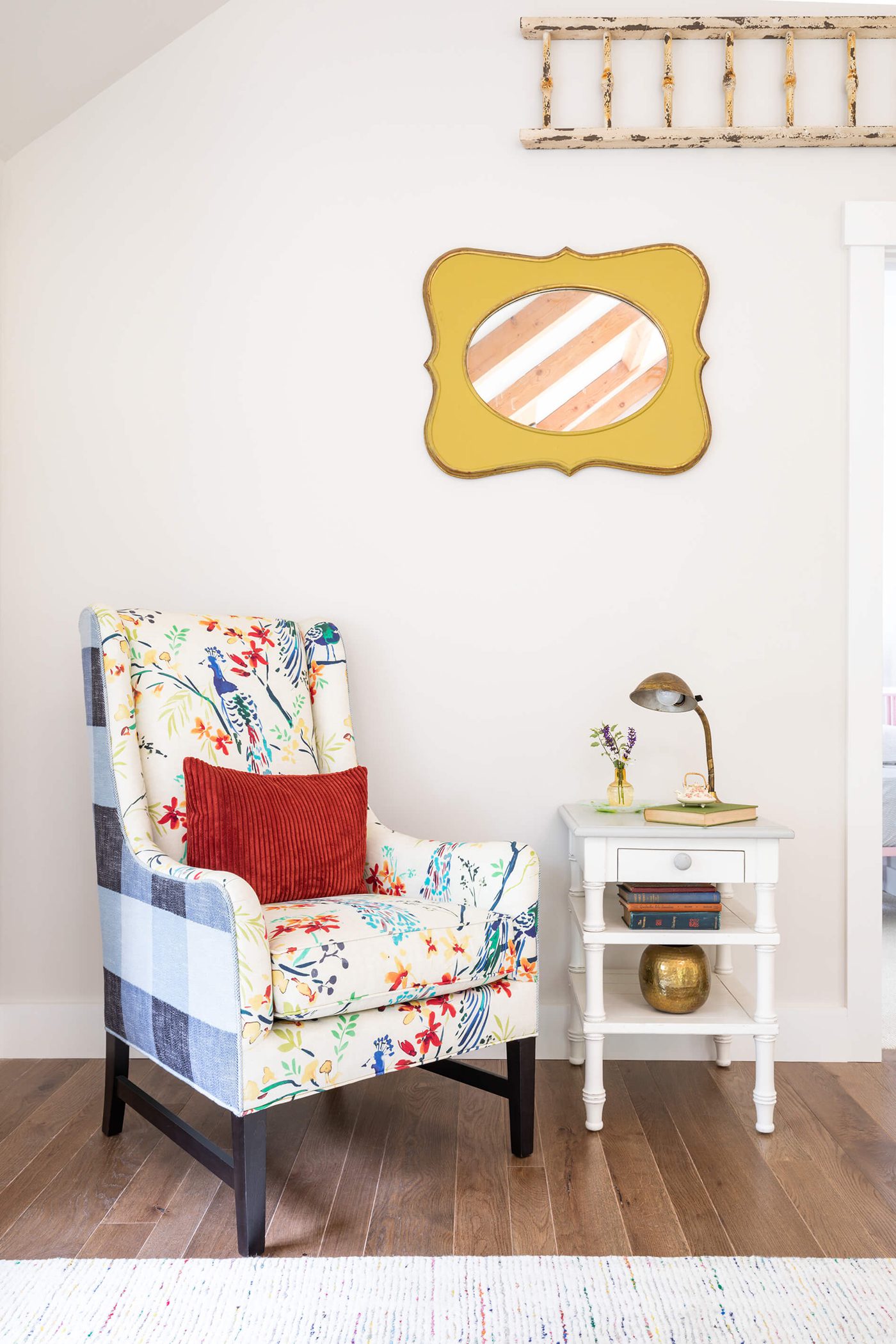 A colorful gingham and floral patterned arm-chair with a white side table in front of a white paint wall.