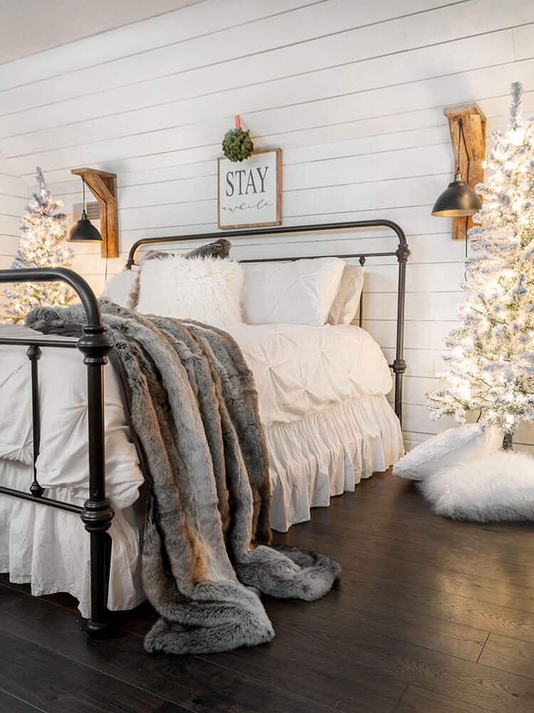 flocked faux Christmas trees on either side of a farmhouse bed
