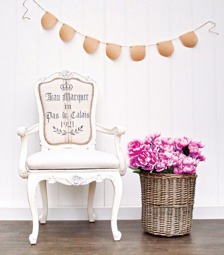 Off-white, antique chair with distressed paint style and grain sack fabric back with royal font.
