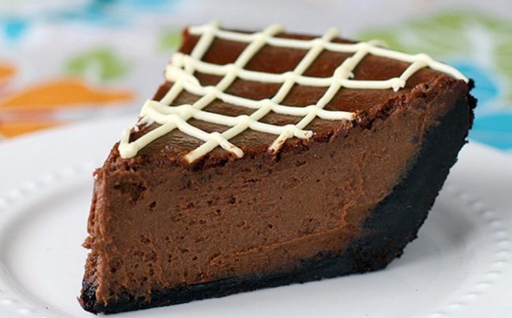 This Thanksgiving recipe shows a slice of chocolate pumpkin pie with a dark chocolate crust and cross-hatched white chocolate stripes on top.