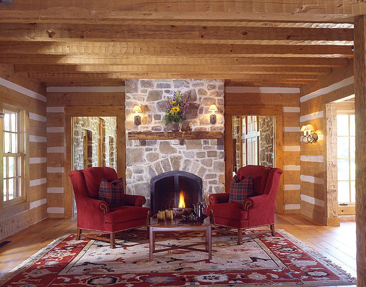 Two red chairs face each other in front of a stone fireplace,