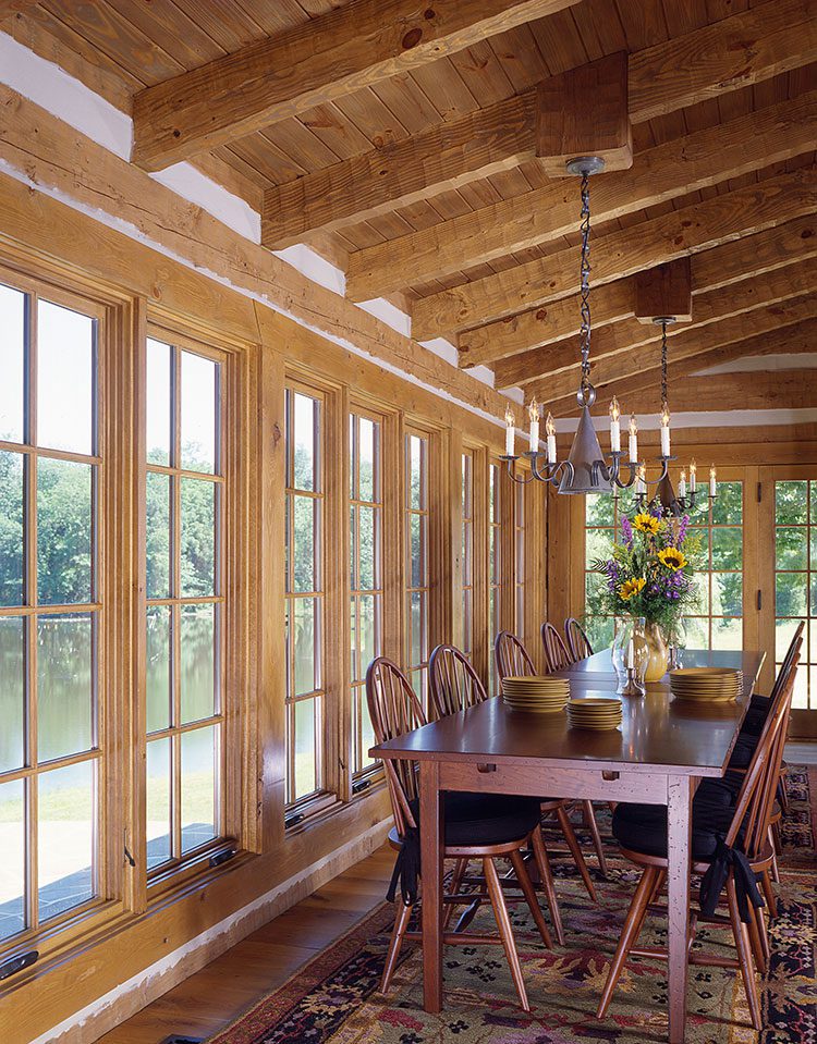 A long dining room table faces a row of windows.