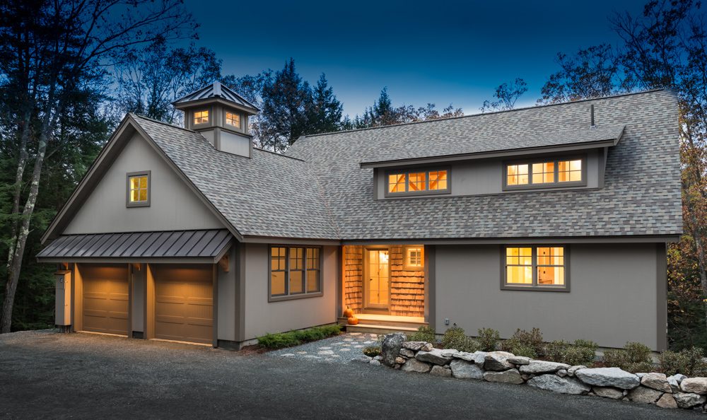 Neutral-painted farmhouse exterior at dusk in New Hampshire.