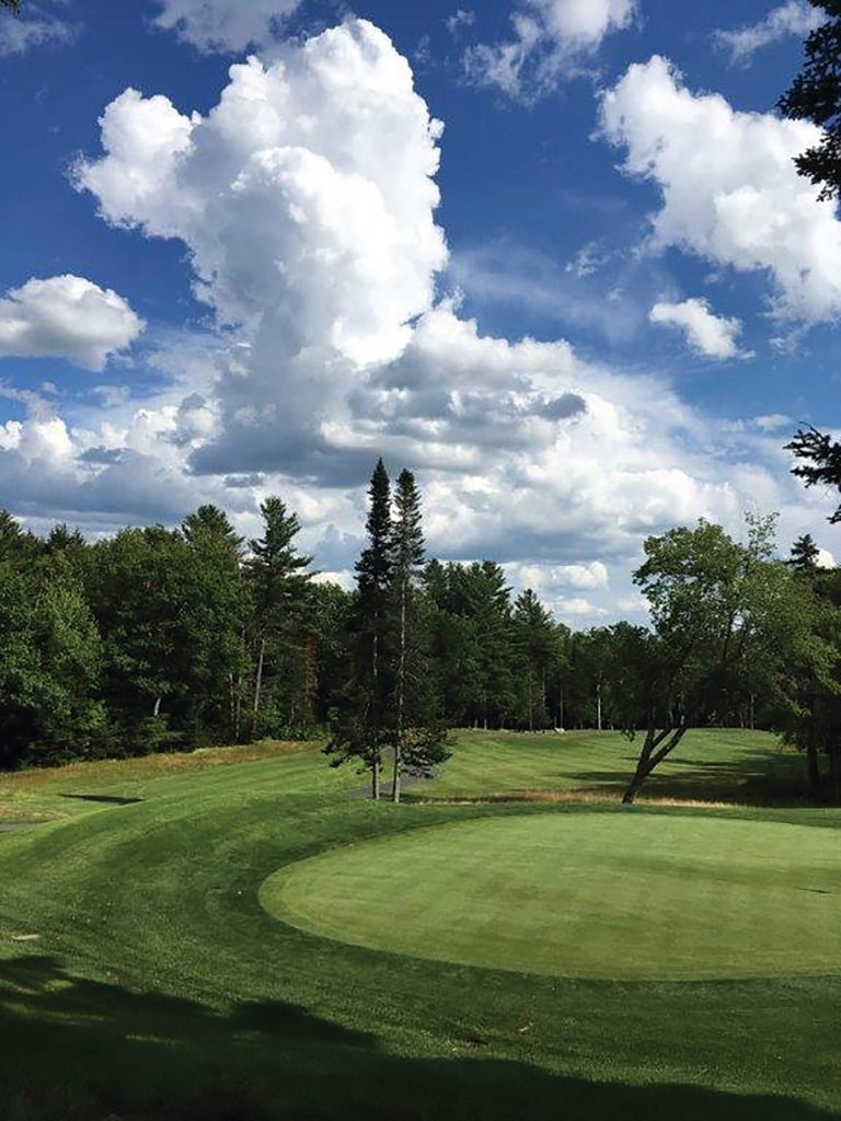 18-hole golf course of the Eastman community in New Hampshire on a semi-cloudy day with a surrounding forest.