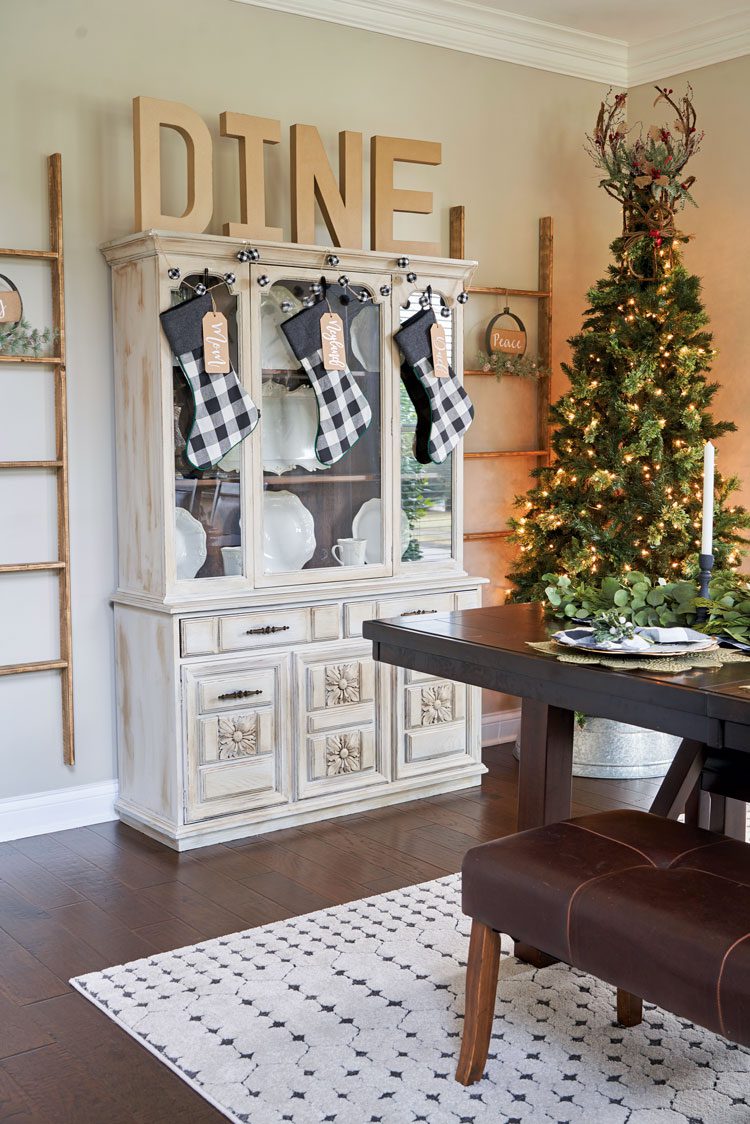 A "DINE" sign rests above the rustic, off-white dining room cabinet.